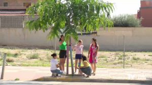 Los niños de Albatera pintan los troncos de los árboles que se encuentra de camino al colegio