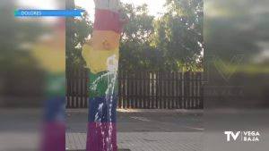 Tiran pintura blanca sobre dos árboles decorados con los colores LGTBI